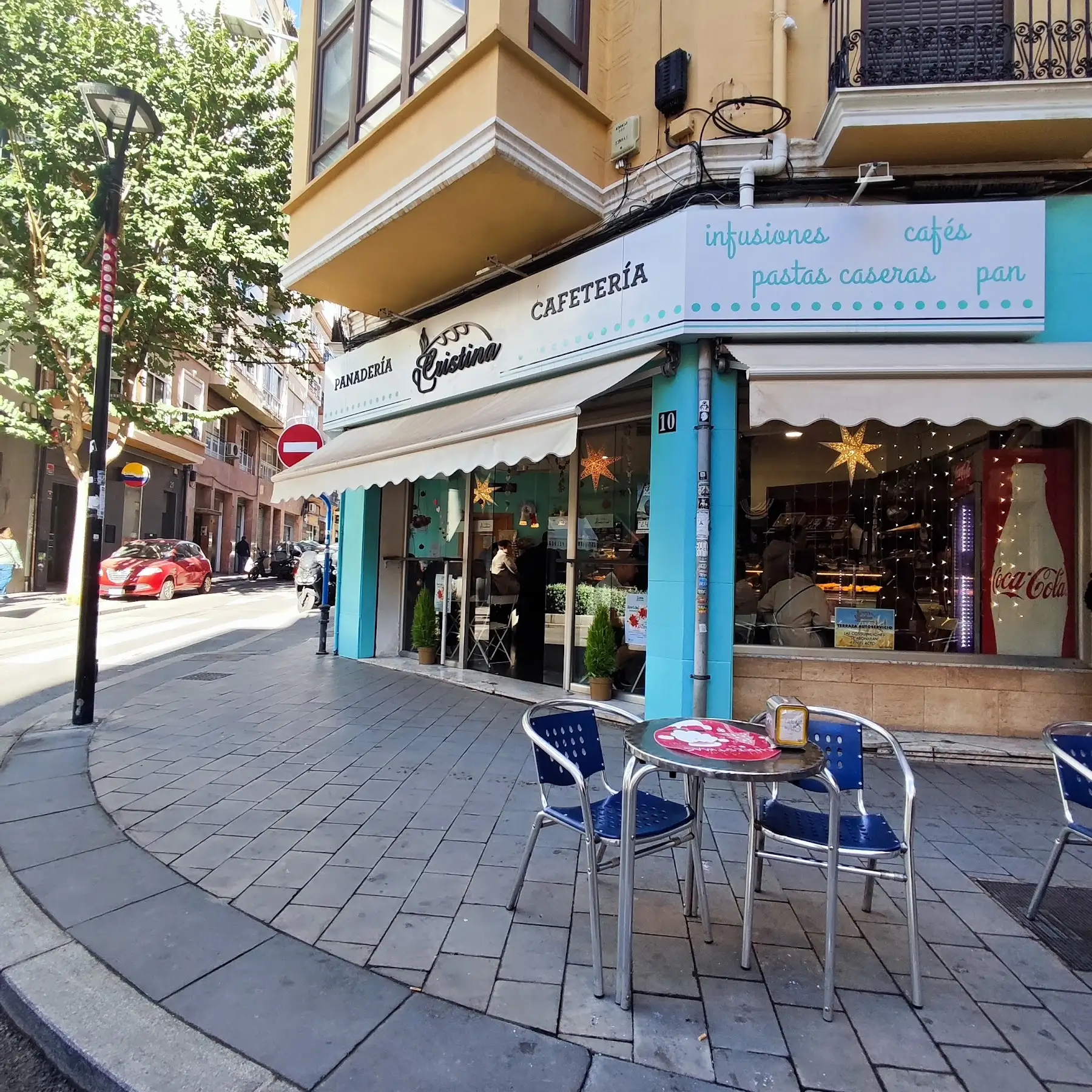 La terraza de la esquina con sillas azules bajo el toldo